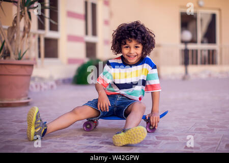 Little Boy With Curly Hair With Skateboard Outdoor Children And