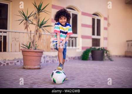 Little boy with curly hair with soccer ball outdoor. Children and entertainment concept Stock Photo