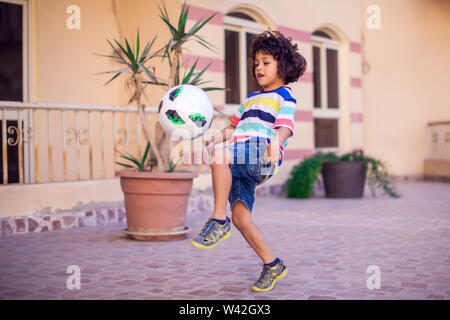 Little boy with curly hair with soccer ball outdoor. Children and entertainment concept Stock Photo