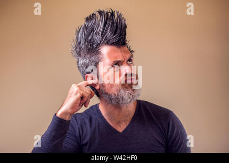 Man with beard and iroquois with finger in ear. People and emotion concept Stock Photo