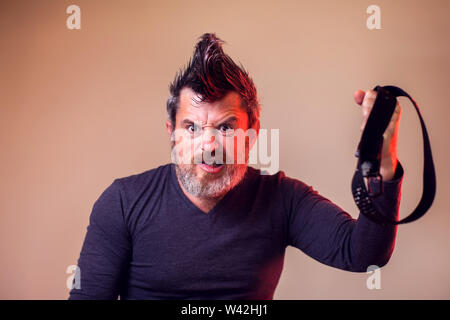Angry bearded man holds belt in hand. Emotions and family violence concept Stock Photo