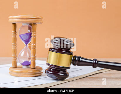 Judge's gavel with hourglass on the table background.