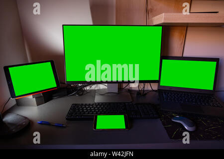 Computer monitor, laptop, tablet and smartphone screens on top of a desktop Stock Photo