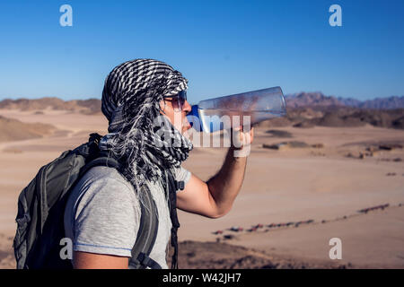 Man feels thirst and drinks water in the desert. Stock Photo
