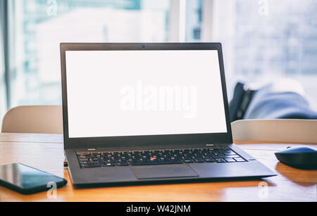 Blank screen computer laptop on a wooden desk, blur winddow background, copy space. Modern workspace Stock Photo