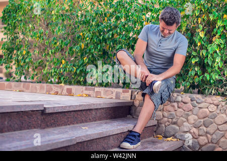 Man feels strong foot pain outdoor. People, healthcare and medicine concept Stock Photo