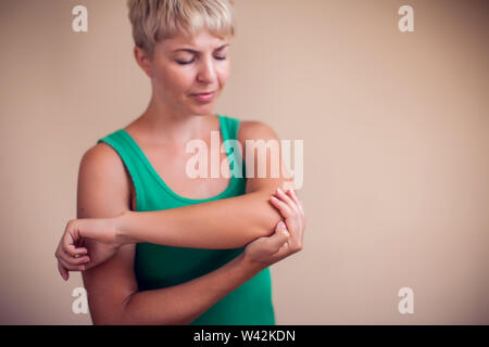 Woman with short hair feels strong elbow pain isolated. People, healthcare and medicine concept Stock Photo