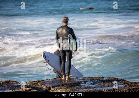 Surfer, man carrying his surfboard ready for a surfing afternoon on Sydney northern beaches,Australia Stock Photo