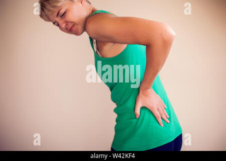 Woman with short hair feels strong pain in back isolated. People, healthcare and medicine concept Stock Photo