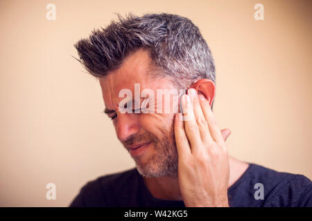Man feels strong ear pain isolated. People, healthcare and medicine concept Stock Photo