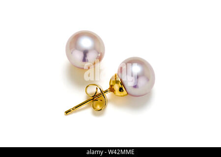 Purple cultured pearls on gold post make up these earring studs. Set on a white background. Stock Photo