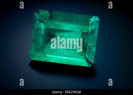 A large natural emerald cut emerald sits on a black reflective background. Stock Photo