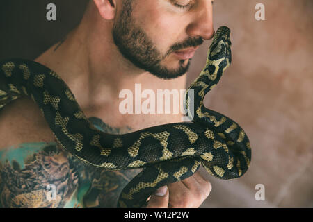 Portrait of man holding a snake near his face Stock Photo