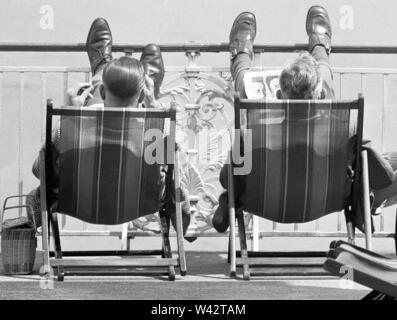 Holiday scenes at Brighton Two holidaymakers put their feet up on Brighton promenade and enjoy the sunny weather. 7th July 1963 Stock Photo