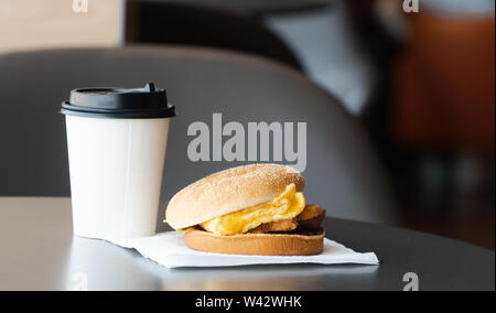 Bacon and Omelette Hamburger on the paper with White paper coffee mug on the table in fast food restaurant Stock Photo