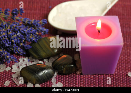 Relax in spa - burning candle, pebbles and lavender flowers. Moody light Stock Photo