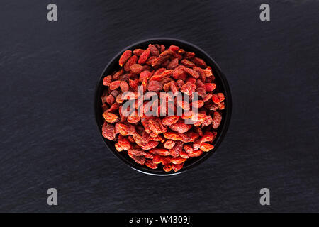 Super brain food dry Goji berry in black ceramic cup on slate stone board with copy space Stock Photo