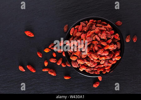 Super brain food dry Goji berry in black ceramic cup on slate stone board with copy space Stock Photo