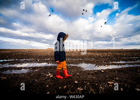 a small boy walking through mud on a wind farm Stock Photo