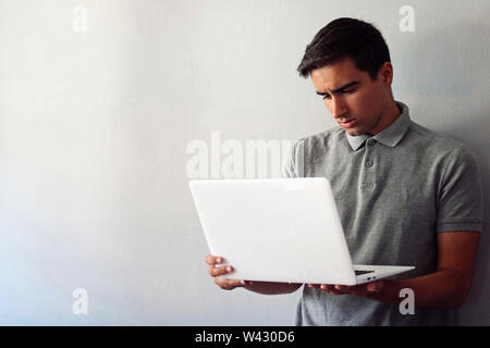 Man dressed in gray using a white laptop. Stock Photo