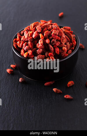 Super brain food dry Goji berry in black ceramic cup on slate stone board with copy space Stock Photo