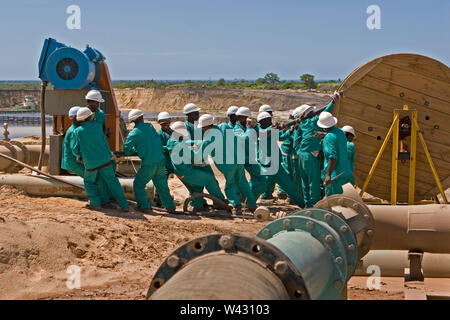 Mining, managing & transporting of titanium mineral sands. Maintenance team laying new power cables at the side of mining pond for wet plant behind. Stock Photo