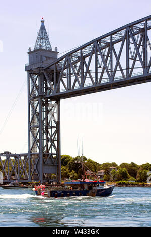 A fishing boat passes under the Cape Cod Canal Railroad Bridge, a vertical lift bridge in Bourne, Massachusetts near Buzzards Bay, Stock Photo