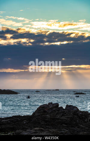 The sun setting over Cobo Bay, Guernsey, Channel Islands UK Stock Photo