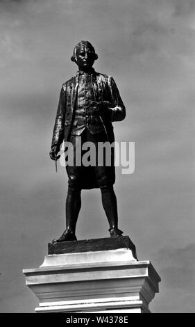 A staute of Captain James Cook stands looking over the harbour at Whitby where the young Cook learnt his trade as a navigator and later ships Captain Stock Photo
