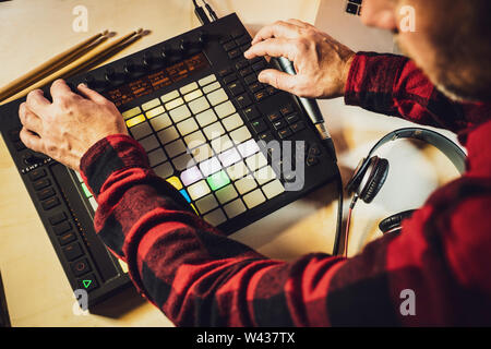 Electronic music production. Looking over the shoulder of a musician as he uses an Ableton Push midi pad controller Stock Photo