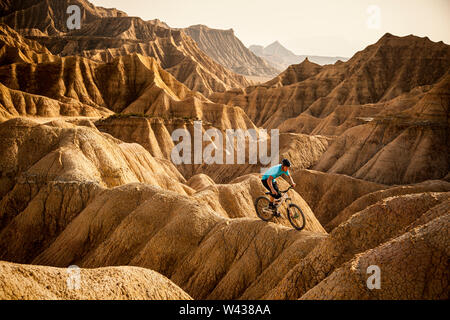 A man rides a mountain bike on a narrow ridge-line trail in the Bardenas Desert. Stock Photo