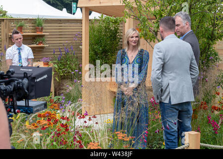 Jo Whiley  doing a piece to camera in the BBC North West Tonight Sunshine Garden In Memory of Dianne Oxberry at RHS Tatton Park flower show 2019. UK Stock Photo