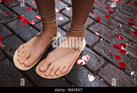 Close-up of a pair of extraordinary wedding shoes.The bride is wearing sandals and is standing in red glitter hearts. Stock Photo