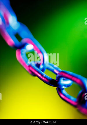 Abstracted short depth of field image of chain links, on a colourful green and yellow background Stock Photo