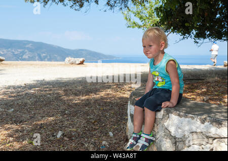 Two year old boy sitting on a rock near Agrilion Monasetery near Sami, Kefalonia, Ionian Islands, Greece, Europe Stock Photo