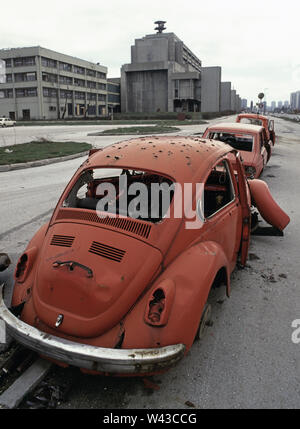 11th April 1993 During the Siege of Sarajevo: shrapnel-damaged cars next to Bulevar Mese Selimovica, at the west end of the BHRT building (television centre). Stock Photo