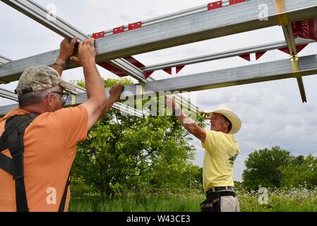 Certified electricians installing a solar electric (photovoltaic) system in a field to generate electricity from the sunlight, Wisconsin, USA Stock Photo