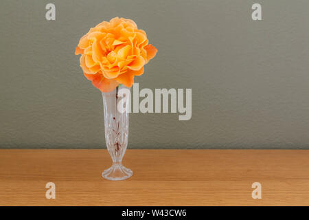 A large Whisky Mac Hybrid Tea Rose cut flower in a cut glass vase Stock Photo