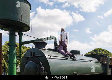 Train driver supervising as a steam locomotive of the Isle of Wight steam railway takes on water. Haven Street station, Isle of Wight, England, UK Stock Photo