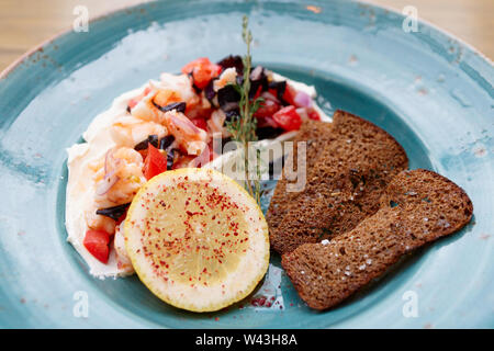 Appetizer of shrimps, tomatoes and sour cream with rye bread toasts Stock Photo
