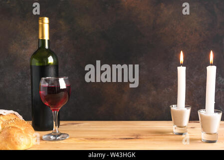 Shabbat or Shabath concept. Challah bread, shabbat wine and candles on table, copy space. Traditional Jewish Shabbat ritual. Stock Photo