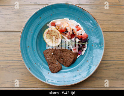 Appetizer of shrimps, tomatoes and sour cream on wooden table Stock Photo
