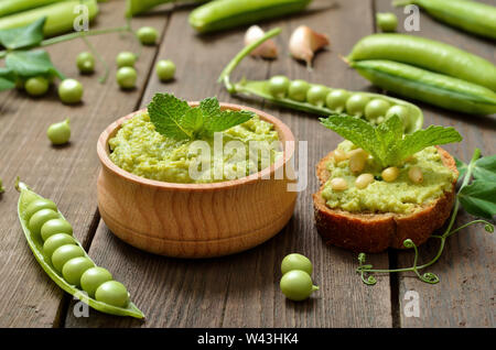 Green pea puree in wooden bowl. Sandwich with green pea puree and pine nuts Stock Photo