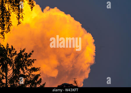 an orange coloured cloud against clear blue skies right before an approaching thunderstorm Stock Photo