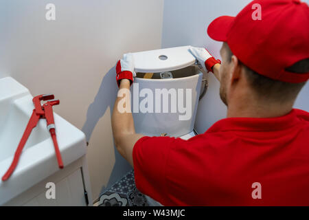 plumbing services - plumber working in bathroom installing toilet wc water tank Stock Photo