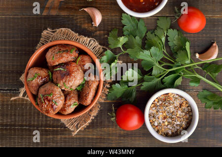 Meatballs in bowl, fresh parsley and tomatoes on wooden table, top view Stock Photo