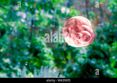 Abstract view of one brown soap bubble on blurred green background. Use for background. Stock Photo