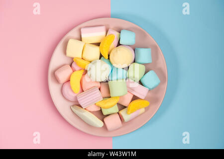 Pink plate with marshmallow, isolated on blue and pink, background. Top view. Stock Photo