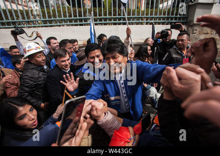 La Paz, Bolivia. 19th July, 2019. Evo Morales (M.), President of Bolivia, greets supporters at the entrance of the Supreme Electoral Court. There he presented his list of candidates for the forthcoming election as a new candidate for the presidency. Bolivia votes on 20 October. The head of state may run again in the next elections and could be re-elected for a fourth term. The Supreme Electoral Court of the South American country allowed the controversial candidacy of the incumbent head of state. Credit: Gaston Brito/dpa/Alamy Live News Stock Photo