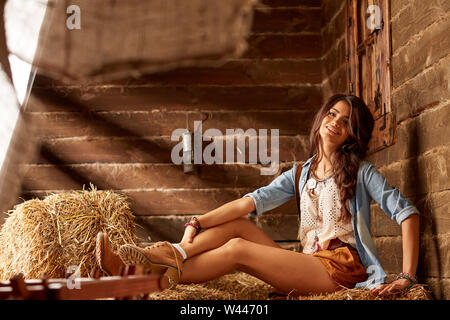 Portrait of confident young woman sitting on hay bales Stock Photo